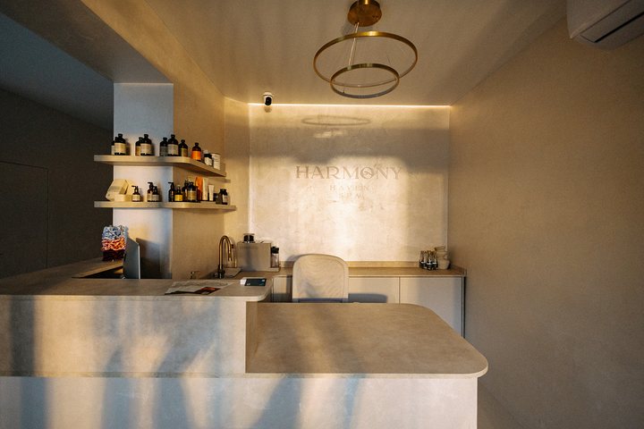 Recepce salonu Harmony Haven Spa se světlým pultem, policemi s kosmetikou a logem na zdi