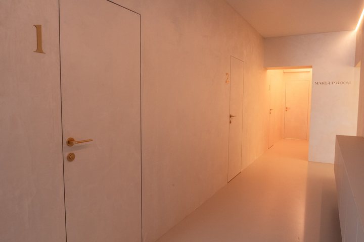 Chodba salonu s očíslovanými dveřmi 1 a 2 a nápisem Make-up room v pozadí
